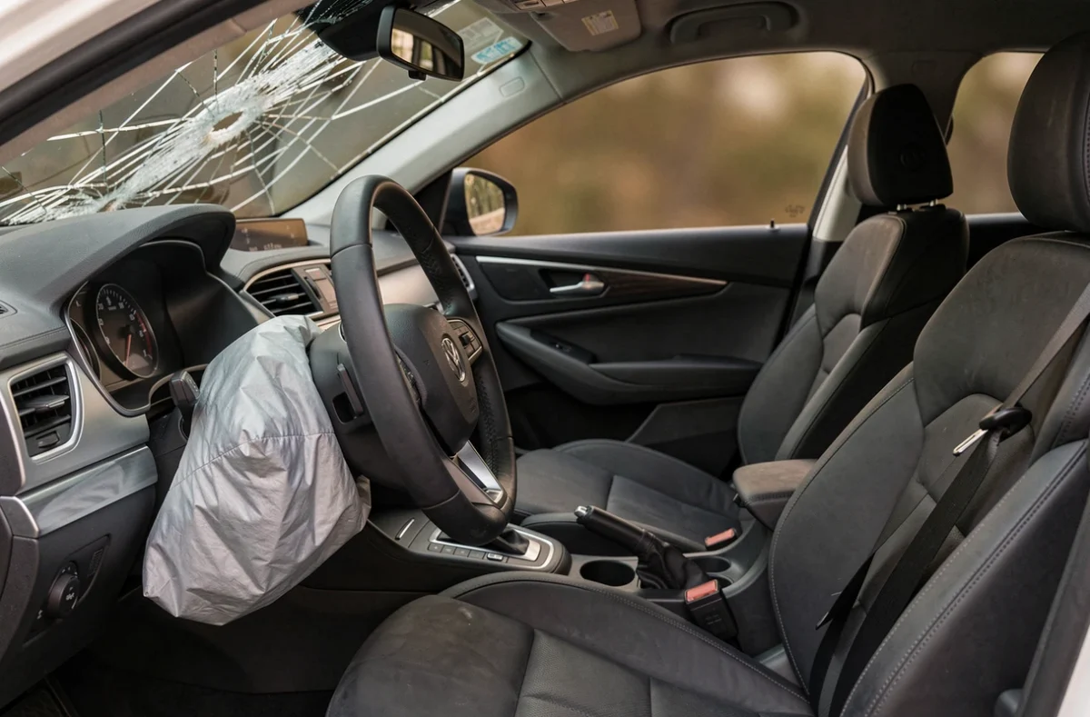 Intérieur de voiture accidentée avec airbag déployé et pare-brise fissuré, symbolisant les dangers mortels de la route