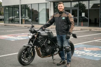 Motard portant une veste homologuée A2 posant à côté d'une moto middleweight devant une auto-école française
