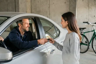 Un homme remet les clés de voiture à une femme, illustrant la notion de conducteur secondaire sur un contrat d'assurance auto